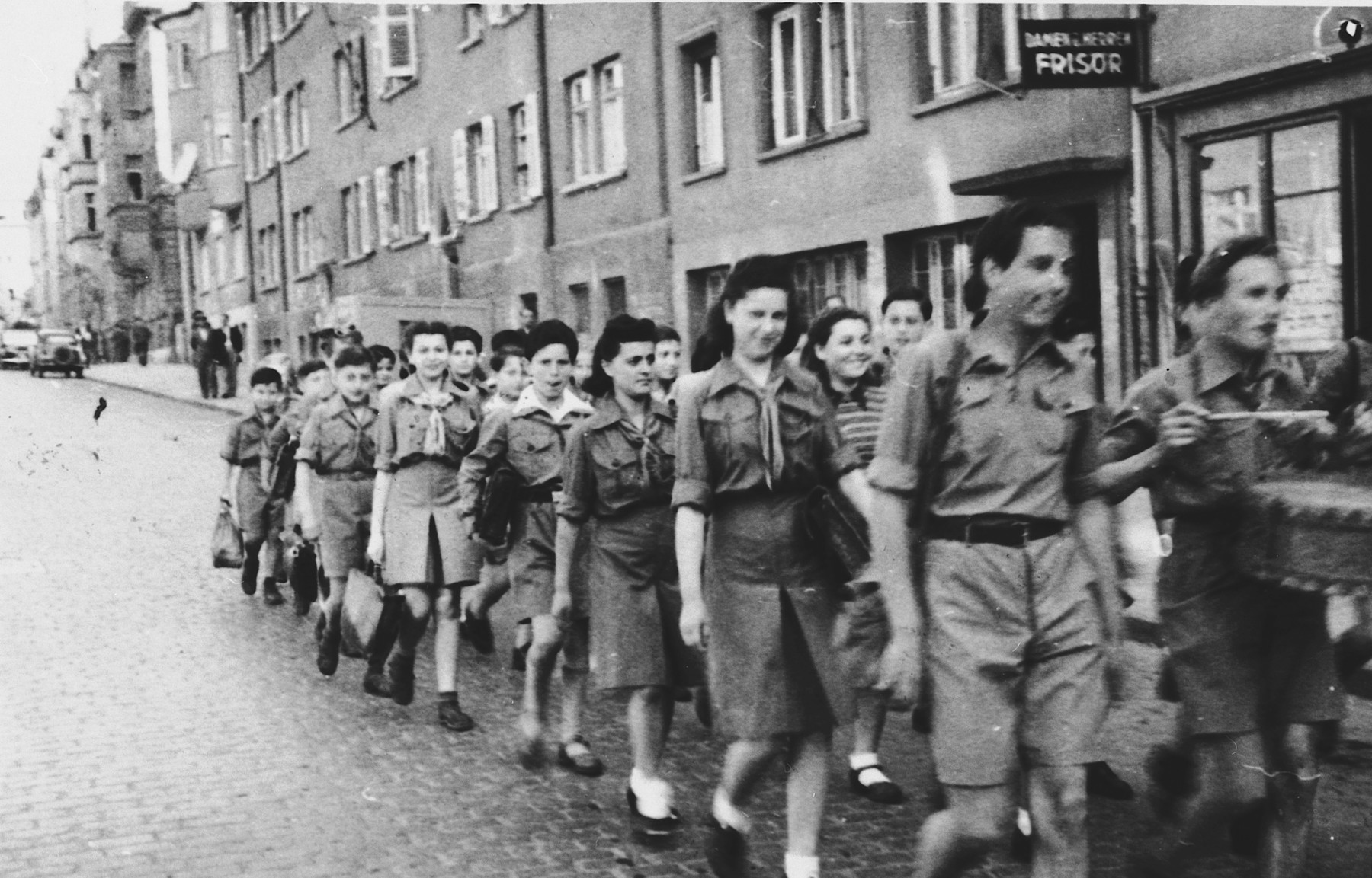 Members of Hashomer Hatzair march in a Zionist demonstration through a commercial street in Stuttgart.

Among those pictured are Basia Kac, second from the left, and Hadasa Eisenberg, fourth from the left.
