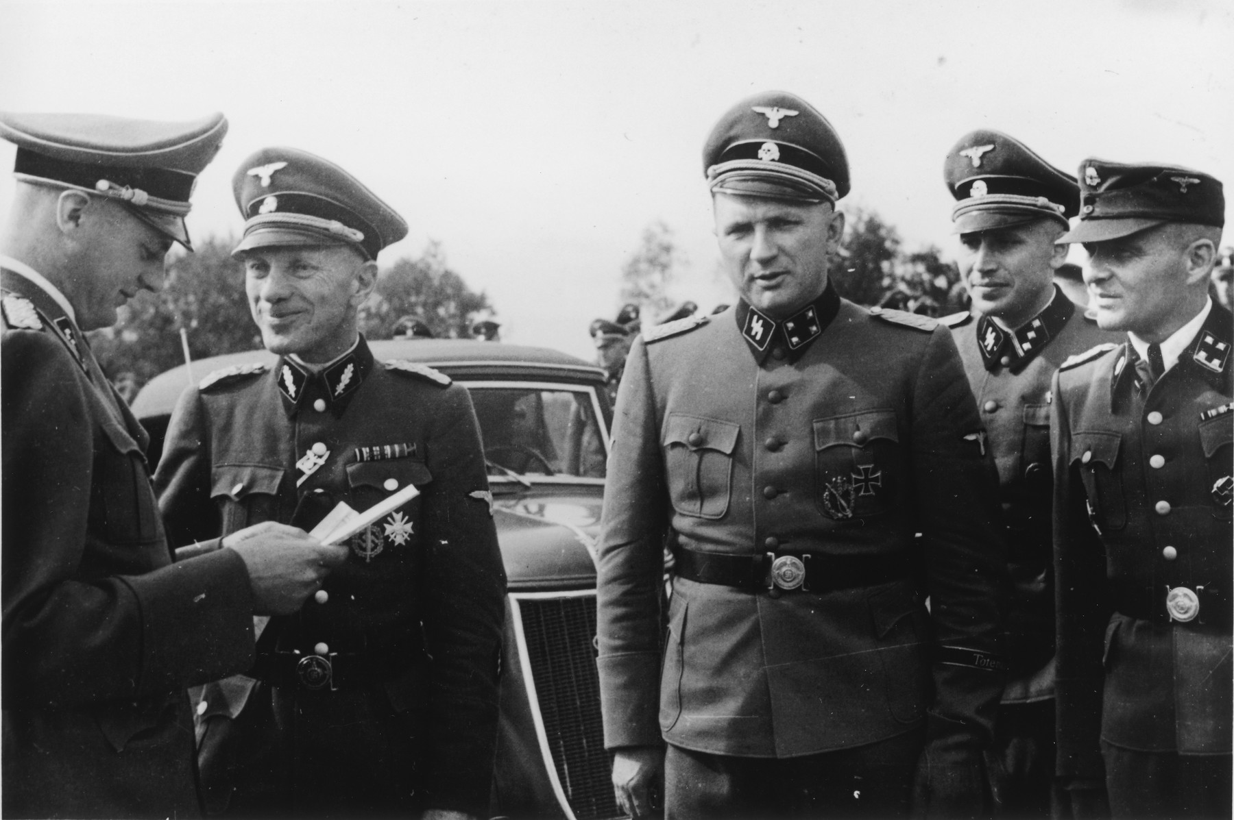 A group of SS officers gathers during the dedication of the new SS hospital.

Pictured left to right are Dr. Eduard Wirths, Dr. Enno Lolling, Commandant Richard Baer, Adjutant Karl Hoecker and former Commandant Rudolf Hoess. 

Dr. Wirths also received his promotion to Sturmbannfuehrer and decorated with the War Service Cross 1st Class at the same time and this might be what is being portrayed here.