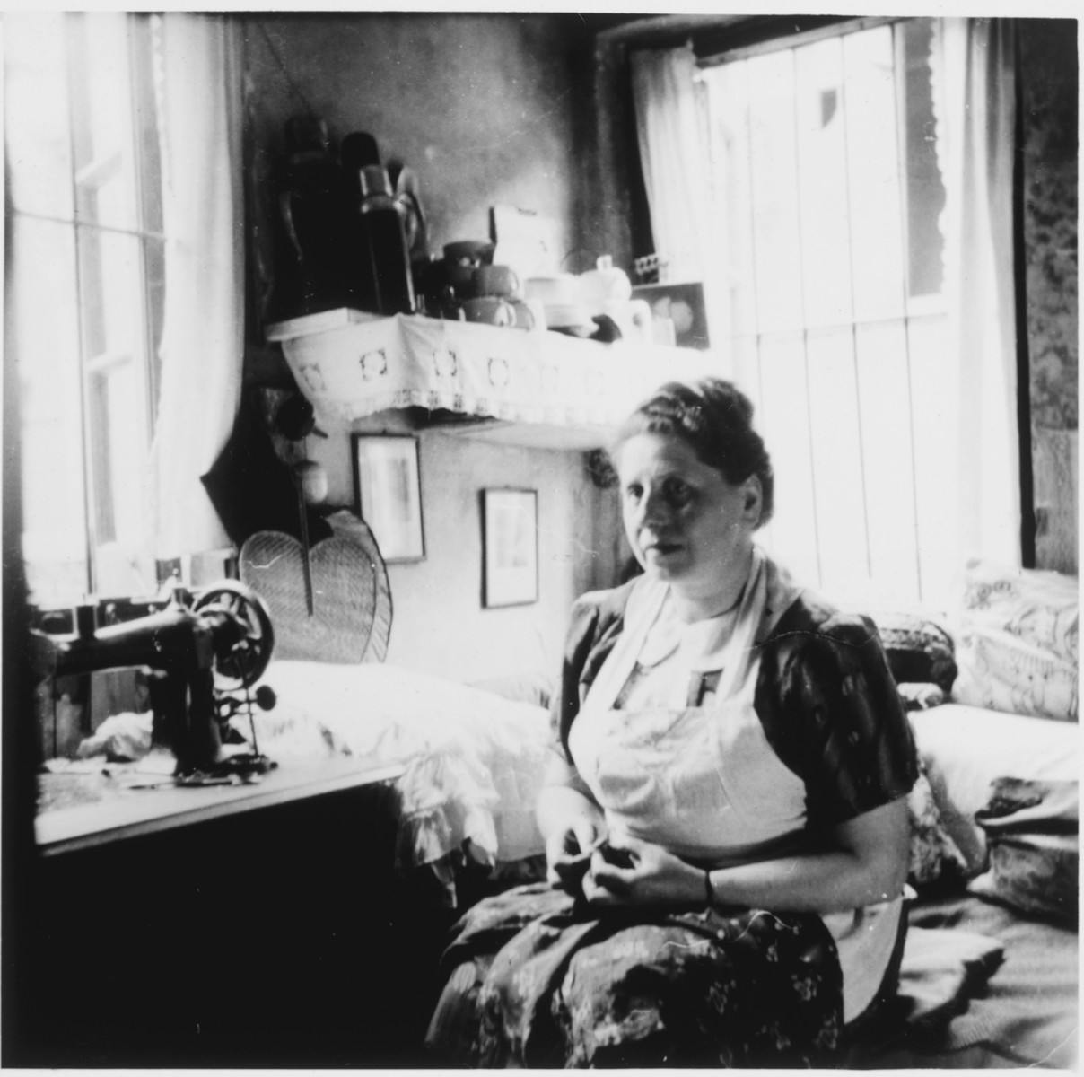 Frau Schoenberg, a German refugee in Shanghai, sits by a sewing machine in her Hongkew apartment.