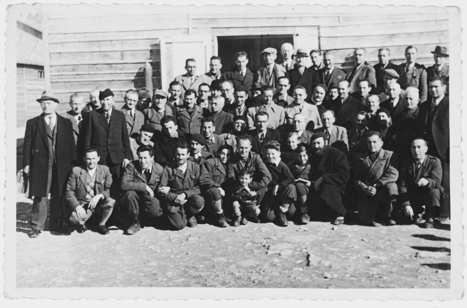 Group portrait of male and child prisoners standing outside their barrack in the Kraljevica concentration camp.

Zlatko Weinrebe is standing on the top row on the far left.