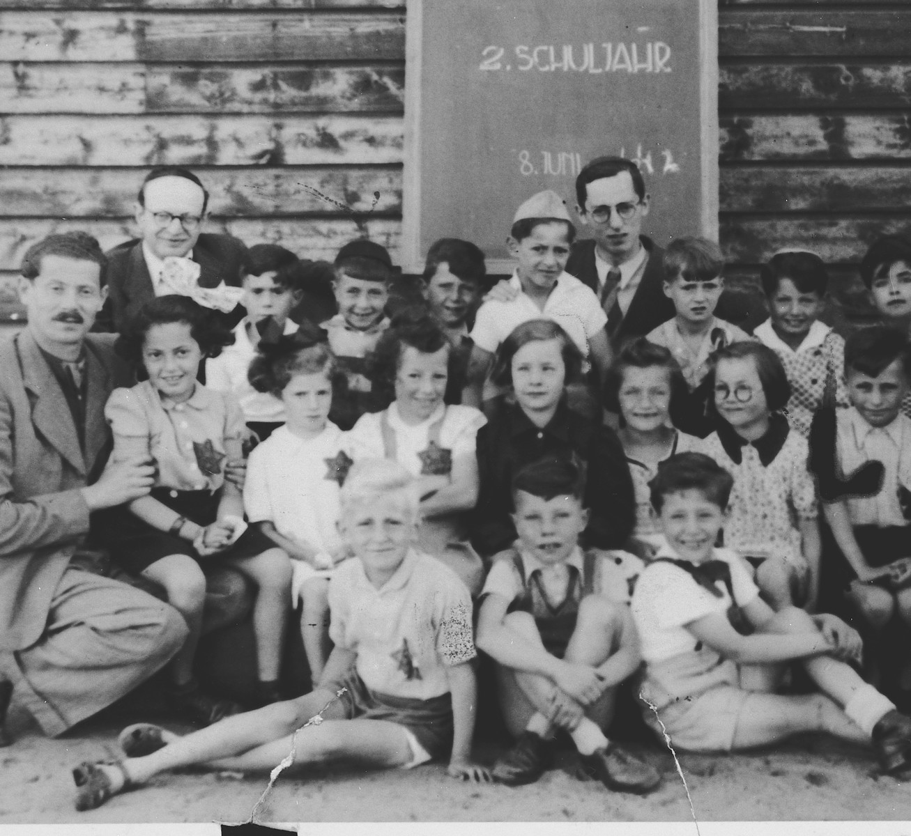 Group portrait of Jewish school children and their teachers, all of whom are wearing Jewish stars, in the Westerbork transit camp.

Among those pictured is Michael Fink (back row center with the white shirt and hat).