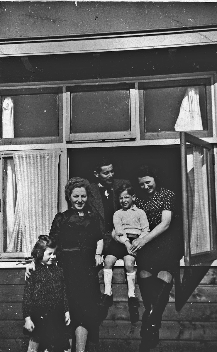 German-Jewish refugees pose in and near the window of one of the barracks of the Westerbork camp.

Among those pictured are Herta Fink and her son Michael, far right.