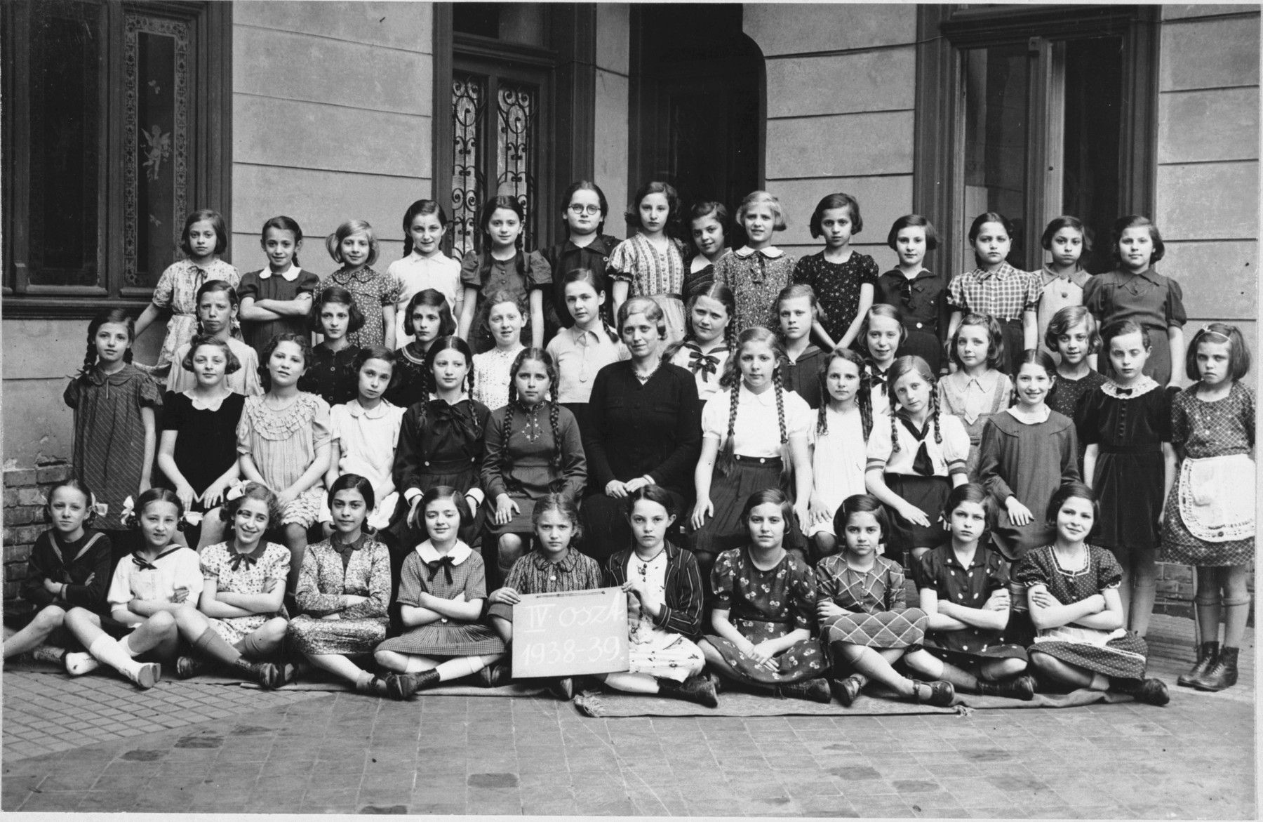 Group portrait of an elementary school class of an Orthodox Jewish school in Budapest which met in the Kazinczy Street Synagogue.

Among those pictured is Anna Roz (top row, fourth from the right.)