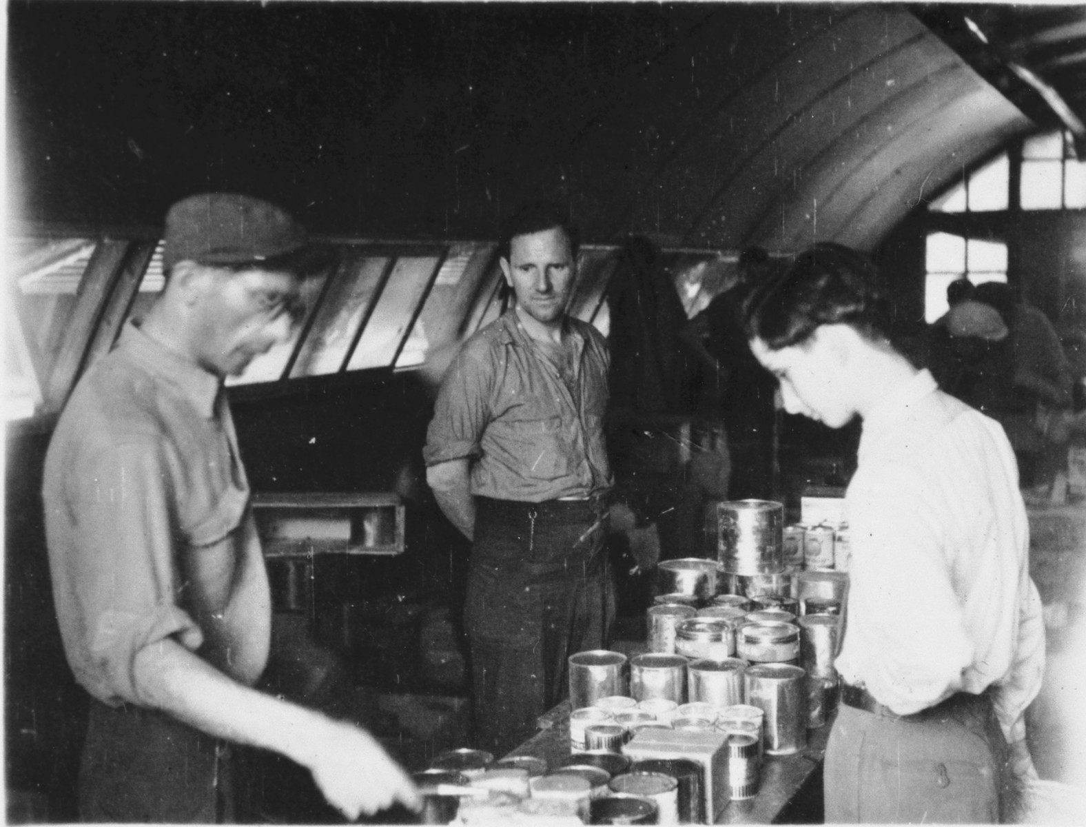Jewish refugees in Shanghai either sort or distribute canned goods inside a quonset hut.