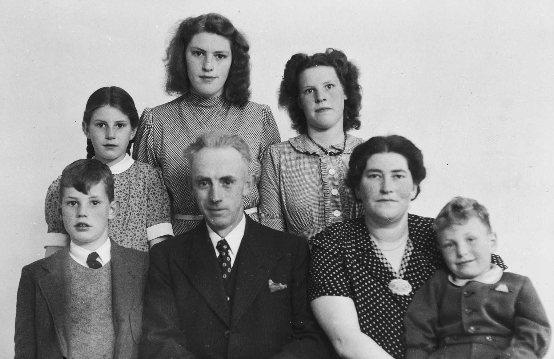 Studio portrait of a family of Dutch rescuers and the Jewish child they were hiding.

Pictured are the family of Berend Philip Bakker and Jeltje Bakker-Woudsma.  The Jewish child, Harry Leo Davids is sitting in the front row on the far right.  Sytske Bakker is standing behind her mother on the right.