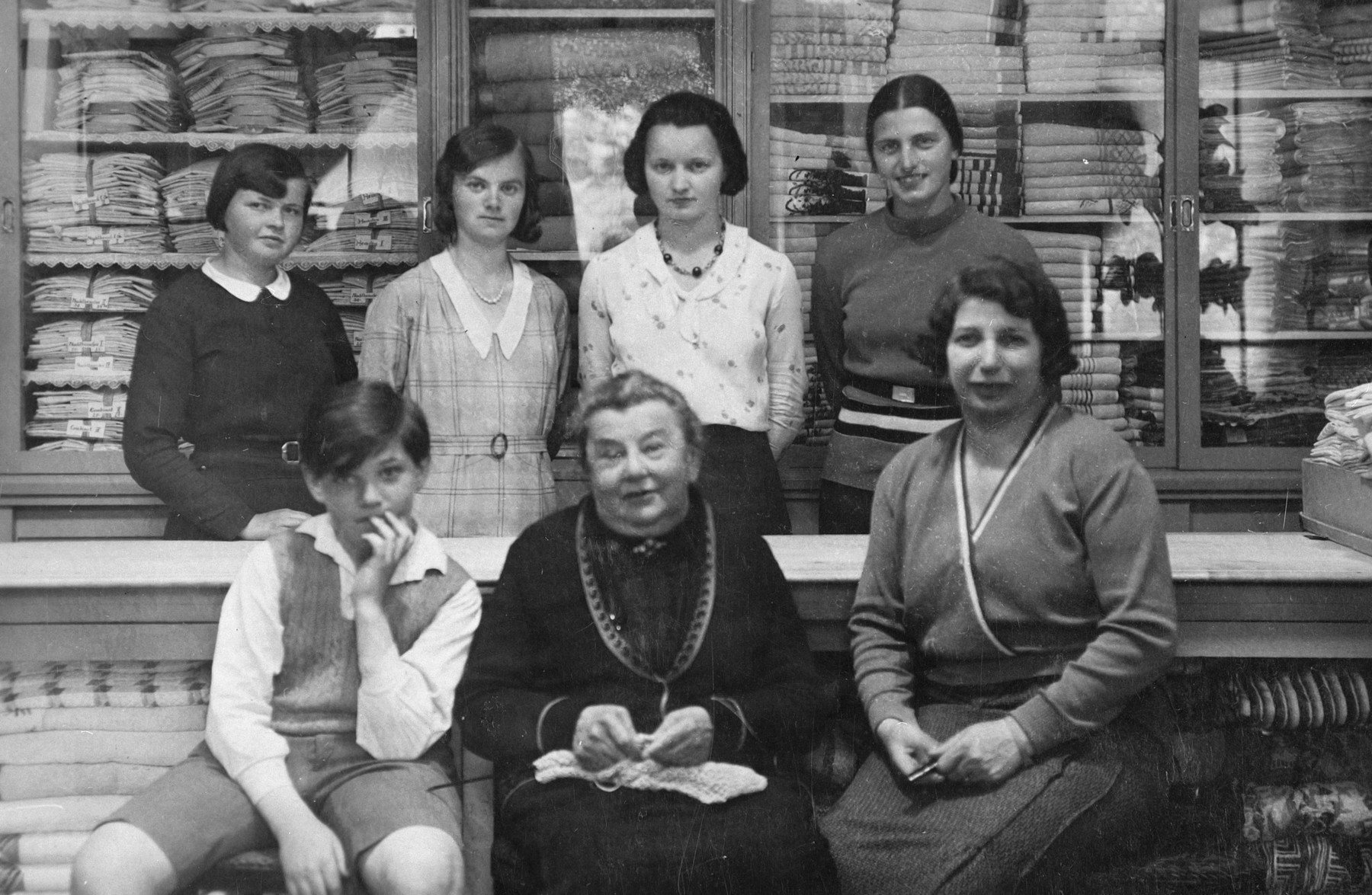 The Jewish owners of a dry goods store in Marienbad pose in front of the counter with other employees standing behind them.

Pictured in the center is Emma Kohn (grandmother of the donor) and on the right is Berta Schleissner (mother of the donor).
