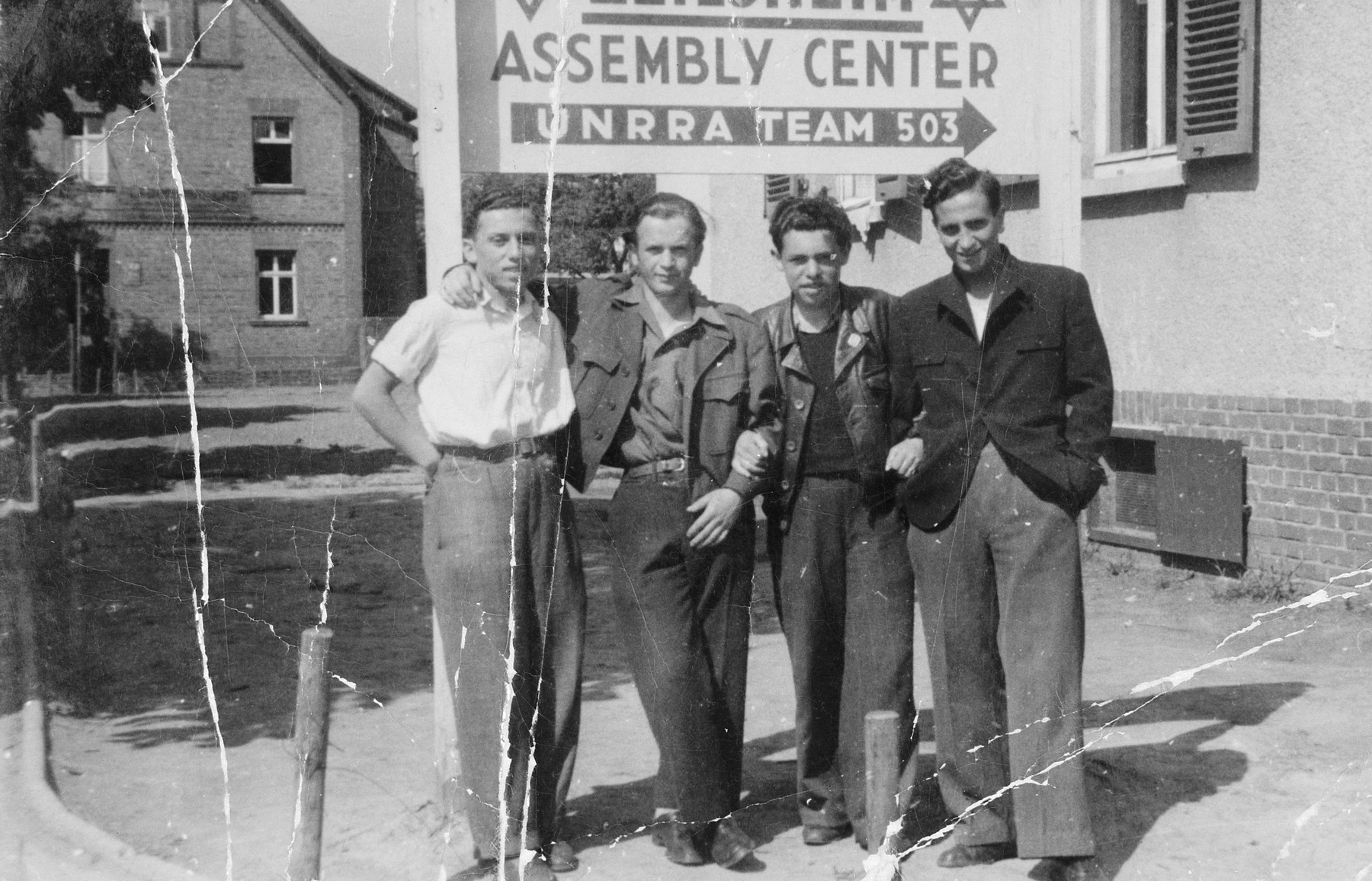 Four young Jewish men stand in front of an UNRRA Assembly Center sign in the Zeilsheim displaced person's camp.

Chuna Grynbaum is on the far right.