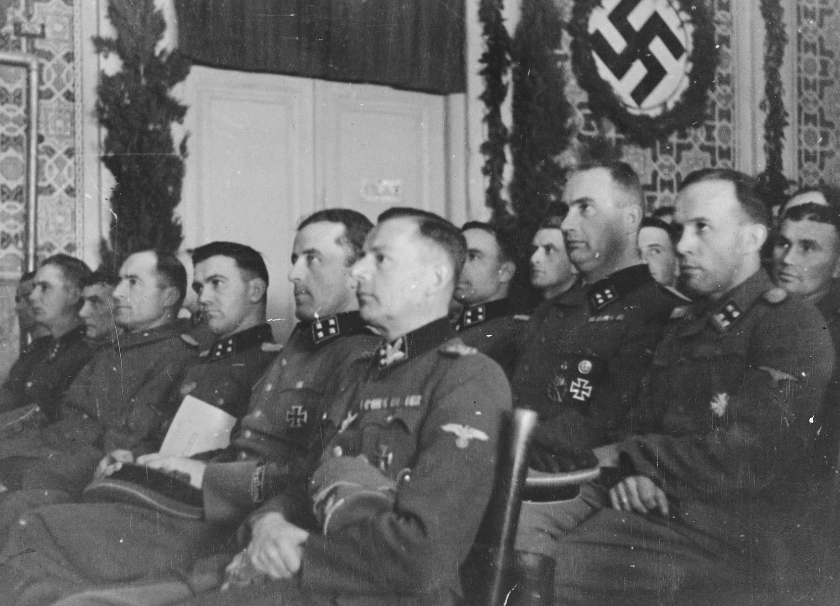 A SS leaders attend a conference in Mostar.

Seated in the first row from right to left are SS-Obergruppenfuehrer Krueger, SS-Sturmbannfuehrer Eberhardt, SS-Sturmbannfuehrer Moreth, SS-Sturmbannfuehrer Hahn. 

The original Waffen-SS caption reads, "Fuehrerbesprechung am 31.1.1944 in Mostar" (leaders' conference on January 31, 1944 in Mostar).

One of a series of photographs taken by the 7th SS Volunteer Mountain Division Prinz Eugen in Croatia, Serbia, and Montenegro from 1942 to 1944, after the German invasion of the Kingdom of Yugoslavia. The photographs are believed to have been captioned by the commanding office of the Waffen-SS, and had been in the possession of  Friedrich Wilhem Krueger, who served with the division from November 1943 until April 1944.