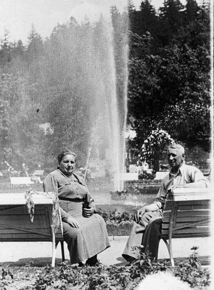 An older Jewish couple sits by a fountain in a park in Krakow before the war.  

Pictured are Fela and Johan Hoffman, (the donor's grandparents).