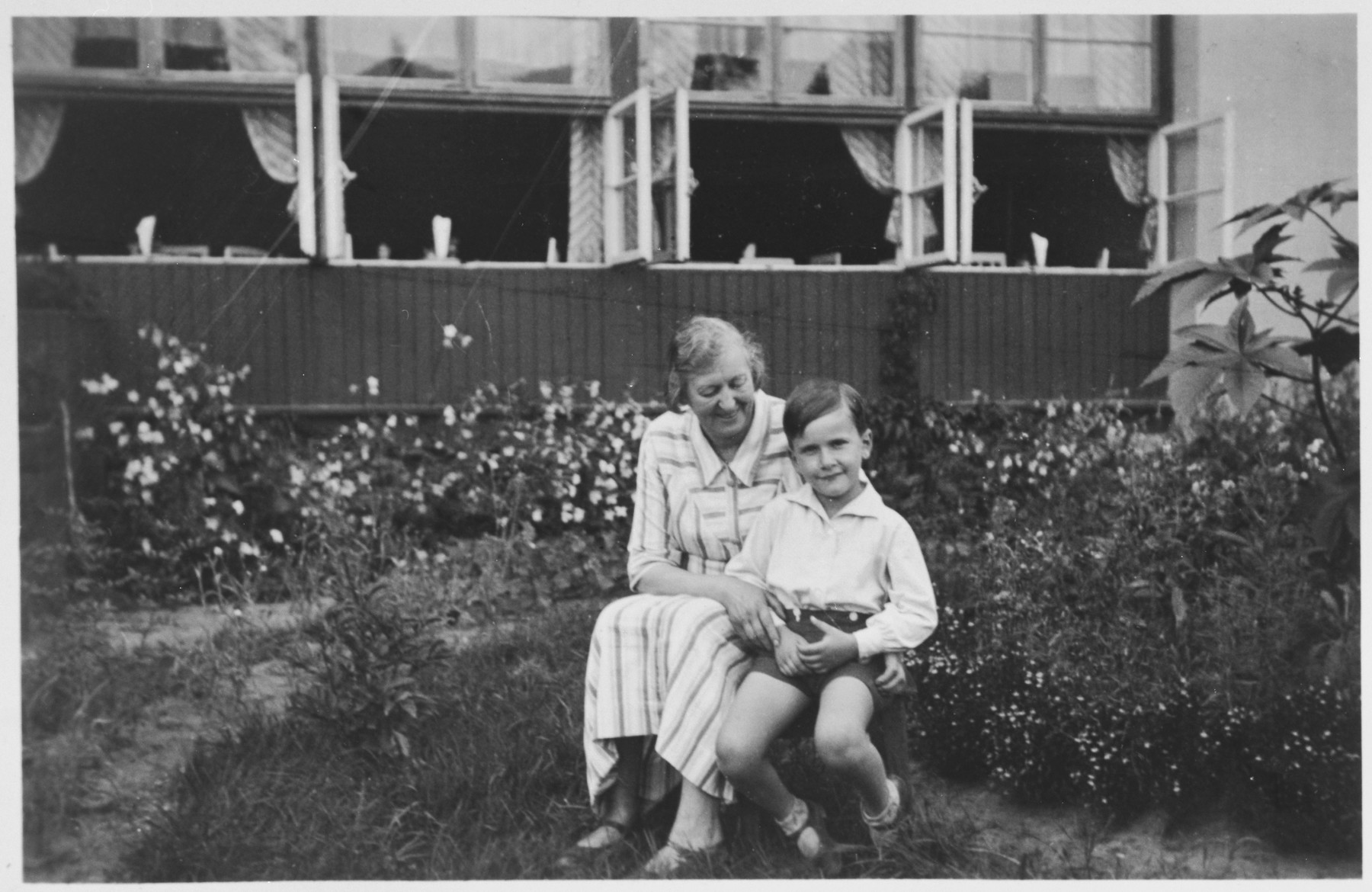 Young Jewish boy poses with his aunt  in the garden of the Sanatorium  run by his family in Druskieniki, Poland (in present day Lithuania).

Pictured are Alexandre Blumstein and his aunt Thea.