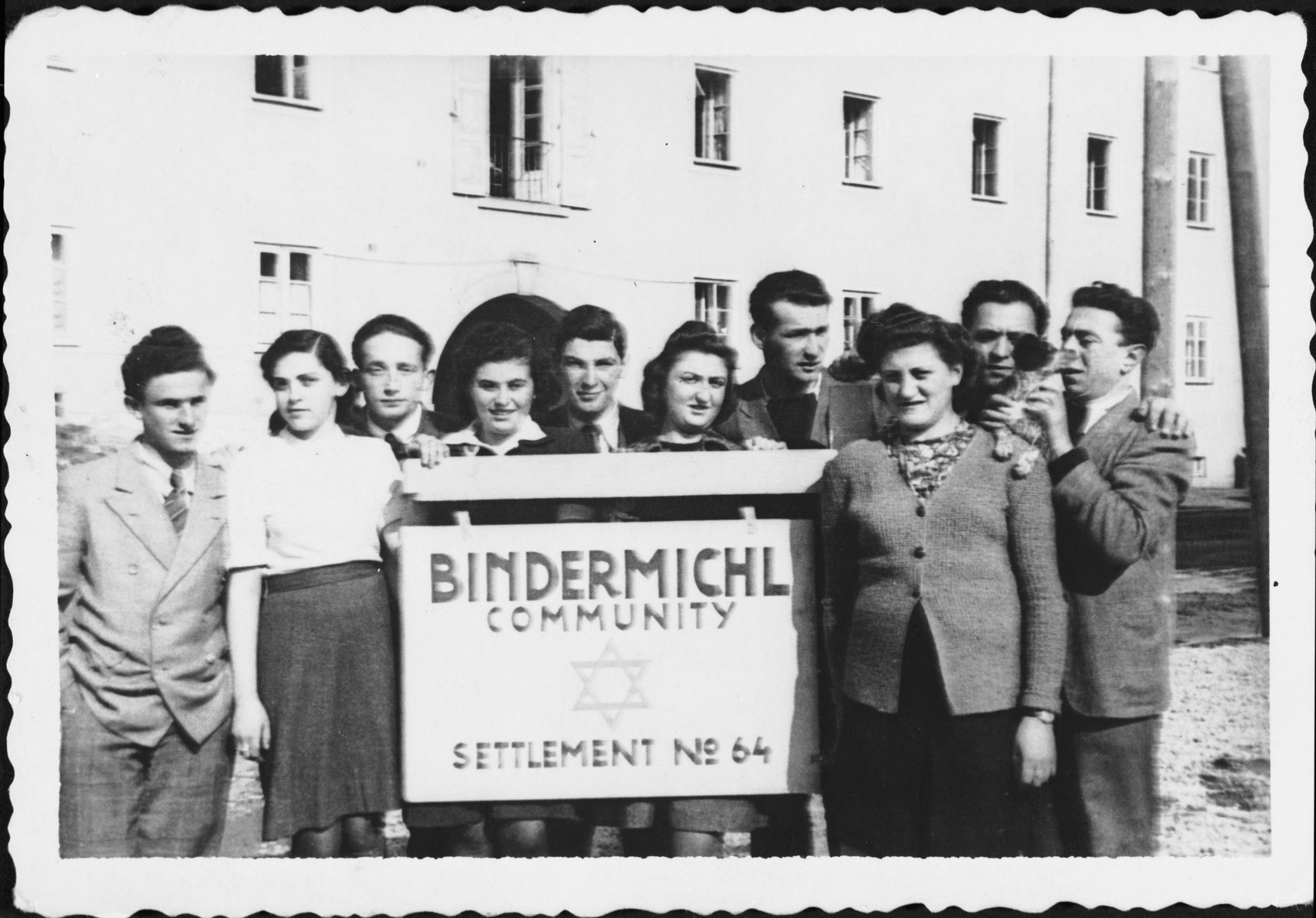 A group of Jewish displaced persons stands next to a sign outside the Bindermichl camp in Linz, Austria.