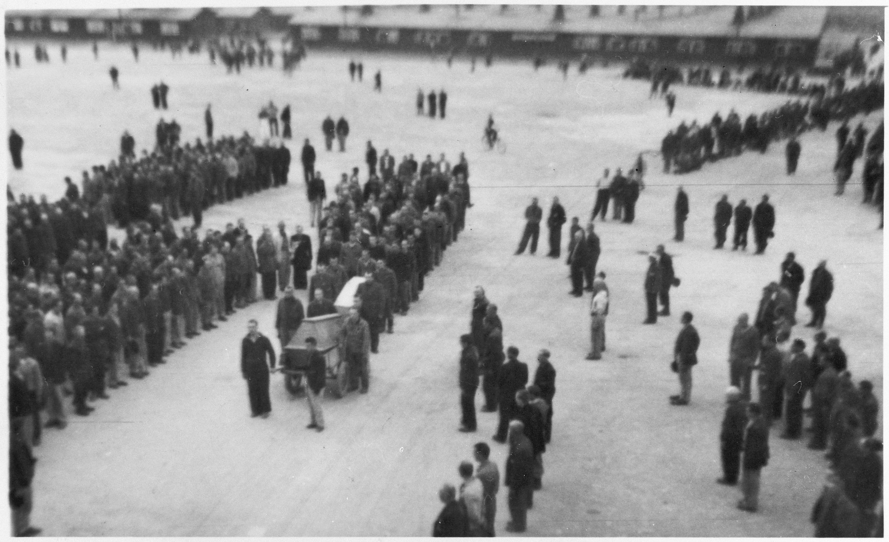 Survivors gather in Buchenwald's main courtyard for the first burial procession at the camp.

Orignial caption reads: "The first burial procession held at Buchenwald's main courtyard."