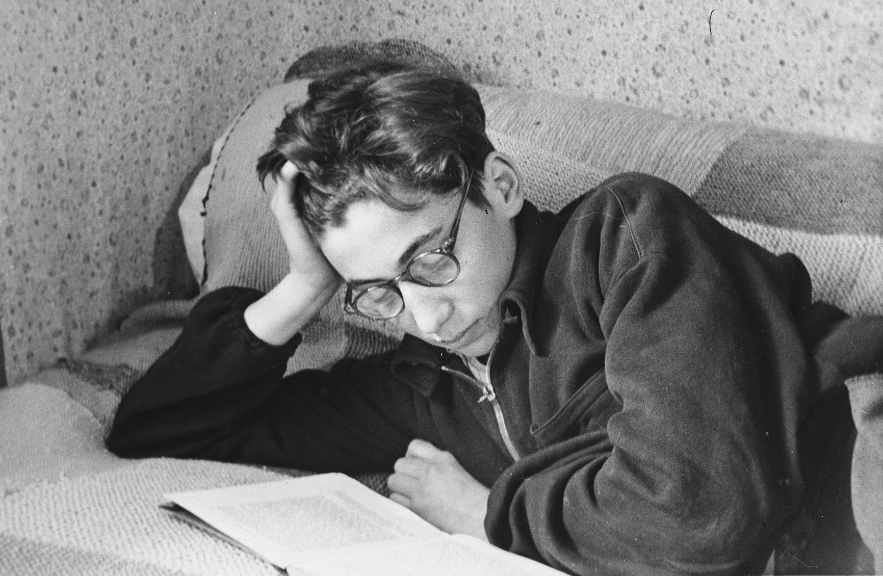 Close-up portrait of a teenage boy reading a book on his bed in a boarding school in Switzerland.

Pictured is a Hungarian survivor, Steven Polgar, the donor's roommmate.