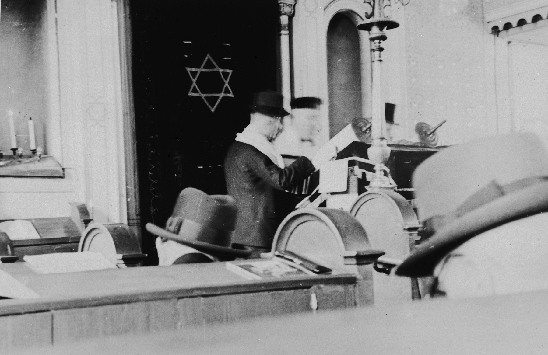 German Jews gather for Sabbath morning prayers in the synagogue in Breisach.

Cantor Michael Eisemann is leading the service.  (Though it is normally forbidden to photograph Sabbath services, an exception was made for the purpose of documenting the community.)

This is part of series of photographs taken of the Breisach Jewish community 1937.  In October 1940 the entire community was deported to the Gurs internment camp in southern France.