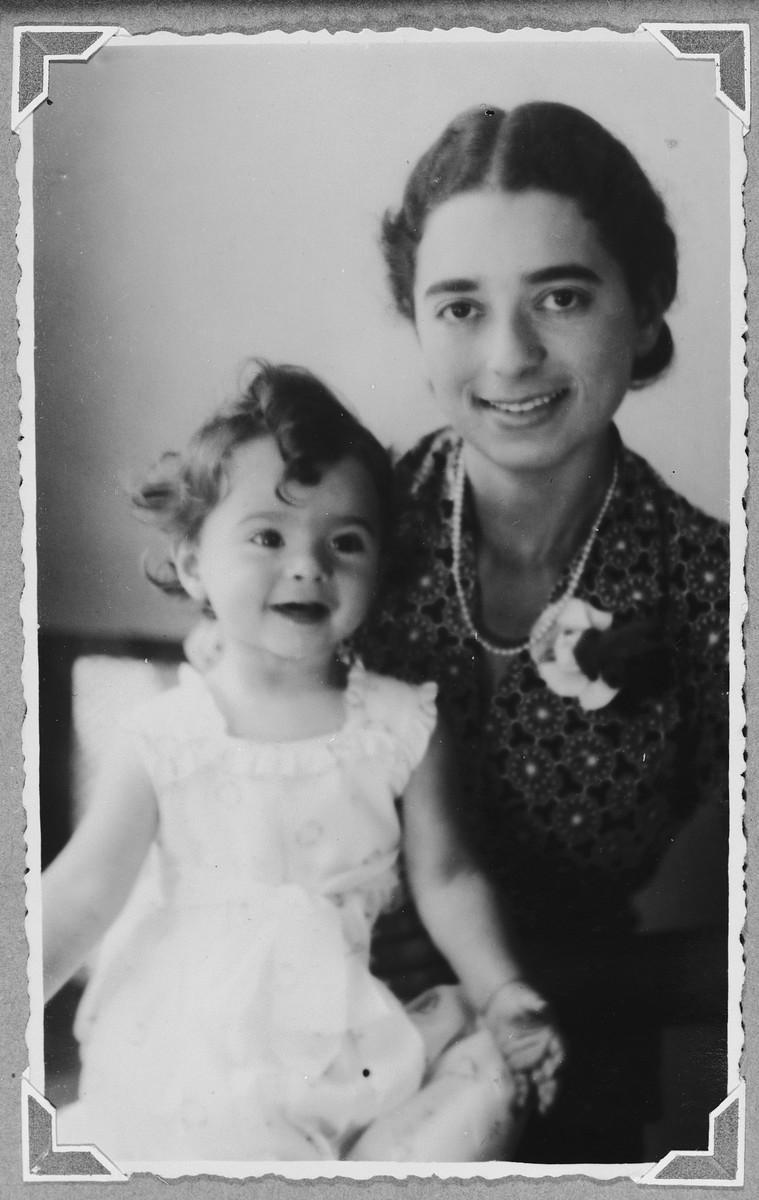 Studio portrait of a German-Jewish refugee in the Netherlands holding her baby girl on her lap.

Pictured are Margot and Suzanne Hochherr.