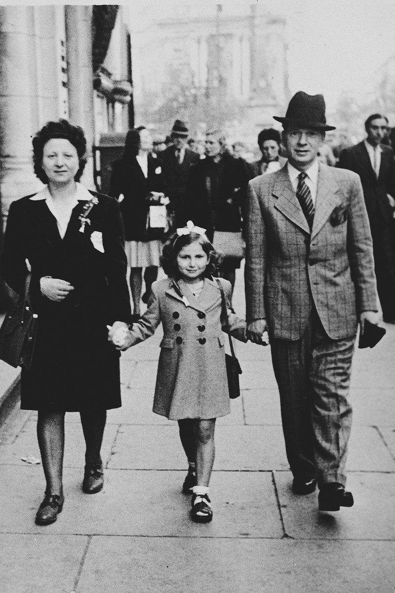 A Belgian-Jewish family walks down a street in Brussels holding hands after being reunited after the war. 

Pictured are Fajga, Josiane and Jacques Aizenberg.