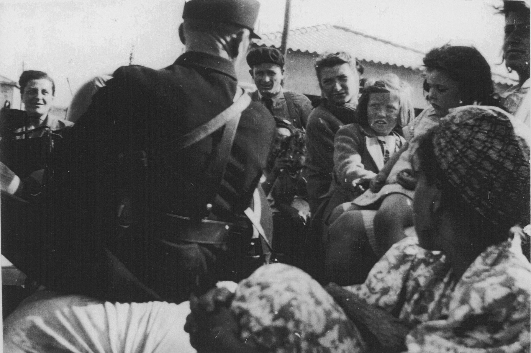 A French policeman directs a group of women and children in the Rivesaltes transit camp during their departure from the camp.