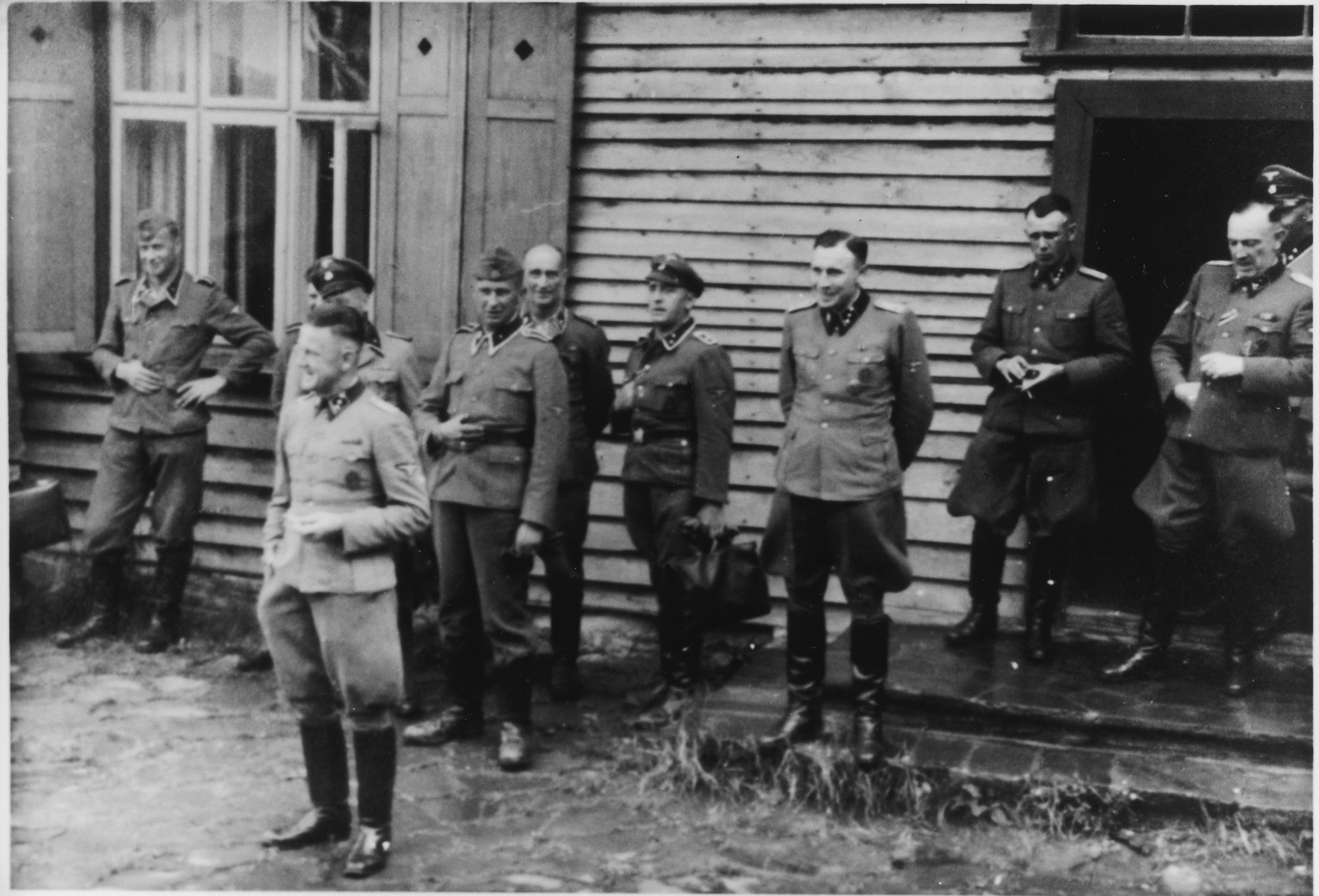 Group portrait of Nazi officers standing in front of a building in Solahutte, the SS retreat outside of Auschwitz.

Among those pictured are Franz Hoessler (front) and Karl Hoecker (third from the right).  Also pictured on the far right is SS-Obersturmführer Max Sell (served from 1943 to1945 first Arbeitseinsatzführer in Auschwitz and afterwards in Mittelbau-Dora.)  Also pictured in the back center is  scha. Hermann Baltasar Buch (30.12.1896-10.07.1959).  From 1943 until September 1944 Buch was in charge of the crematory IV in Birkenau.

[Based on the officers visiting Solahutte, we surmise that the photographs were taken to honor Rudolf Hoess who completed his tenure as garrison senior on July 29.]