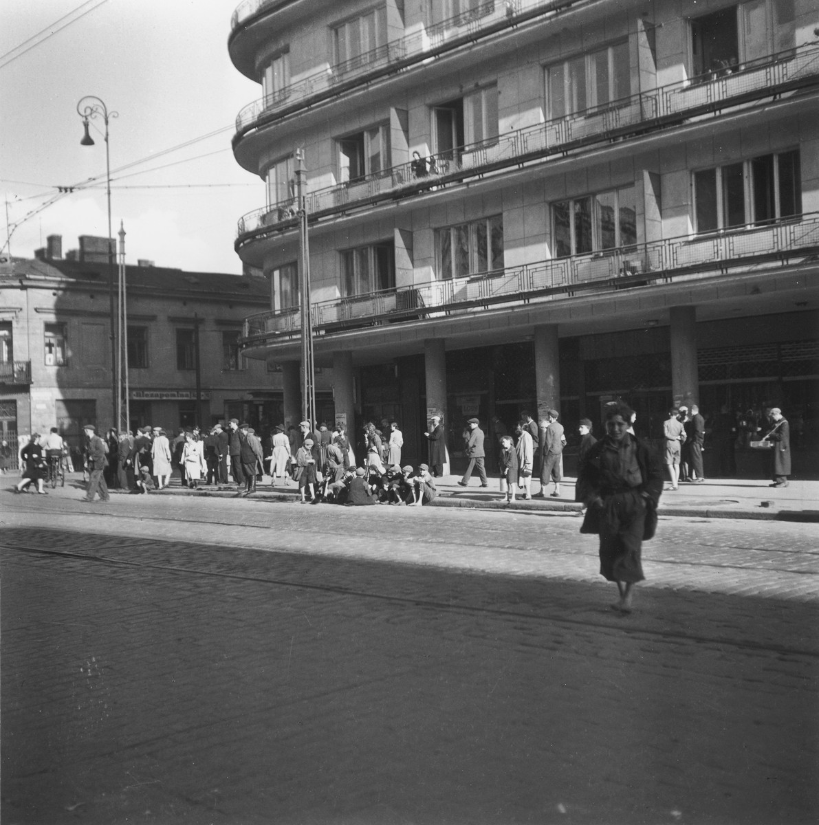 Street scene in the Warsaw ghetto.

Joest's original caption reads: "The same house.  I asked myself: What are all these people waiting for?  They couldn't be waiting for the streetcar; it didn't stop in the Ghetto.  And everywhere countless children without shoes."
