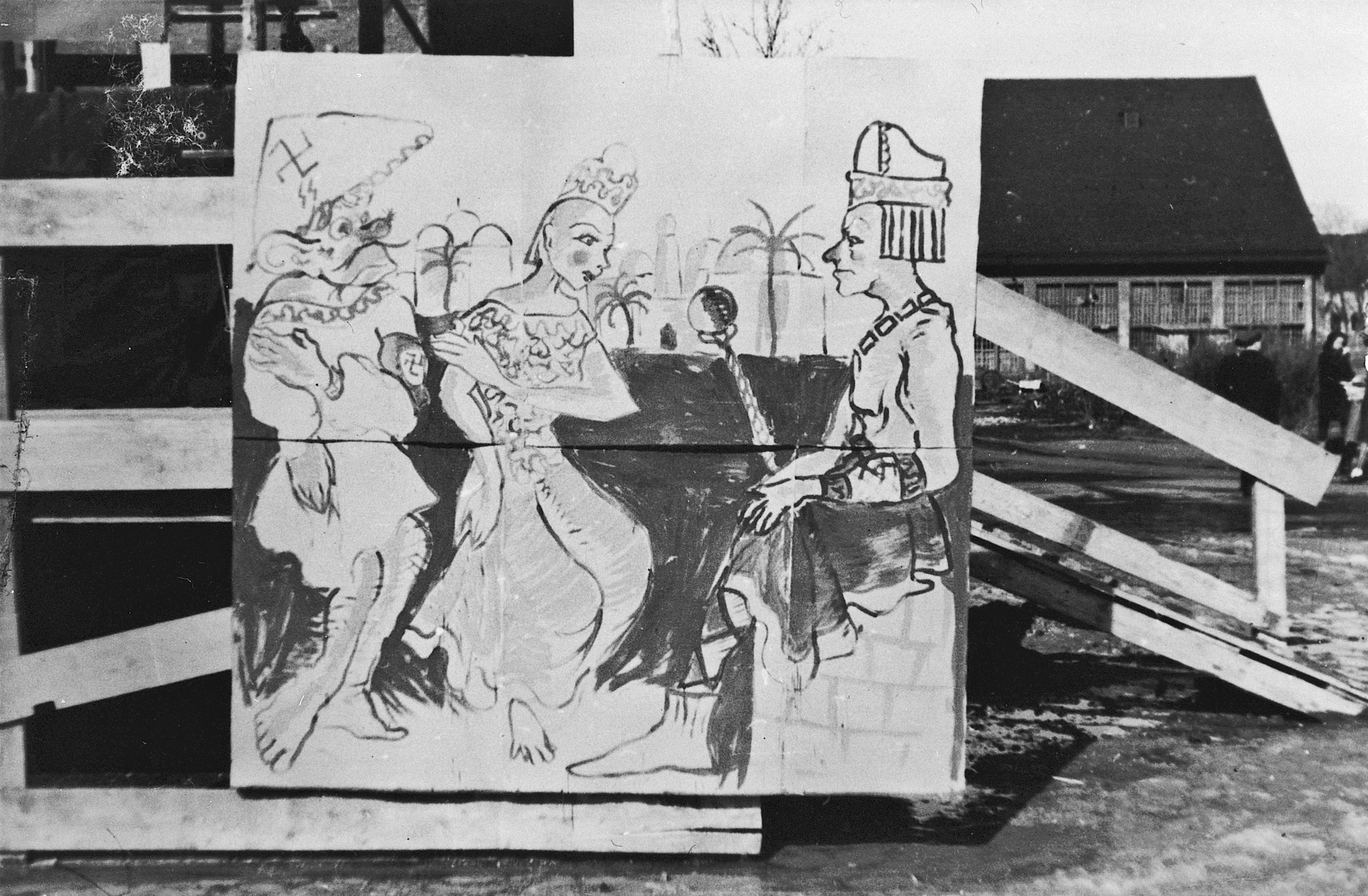 Photograph of a large poster in the Landsberg DP camp displayed during a Purim celebration showing a scene from the Purim story, only with the villain Haman wearing a hat with a swastika and a Nazi armband.