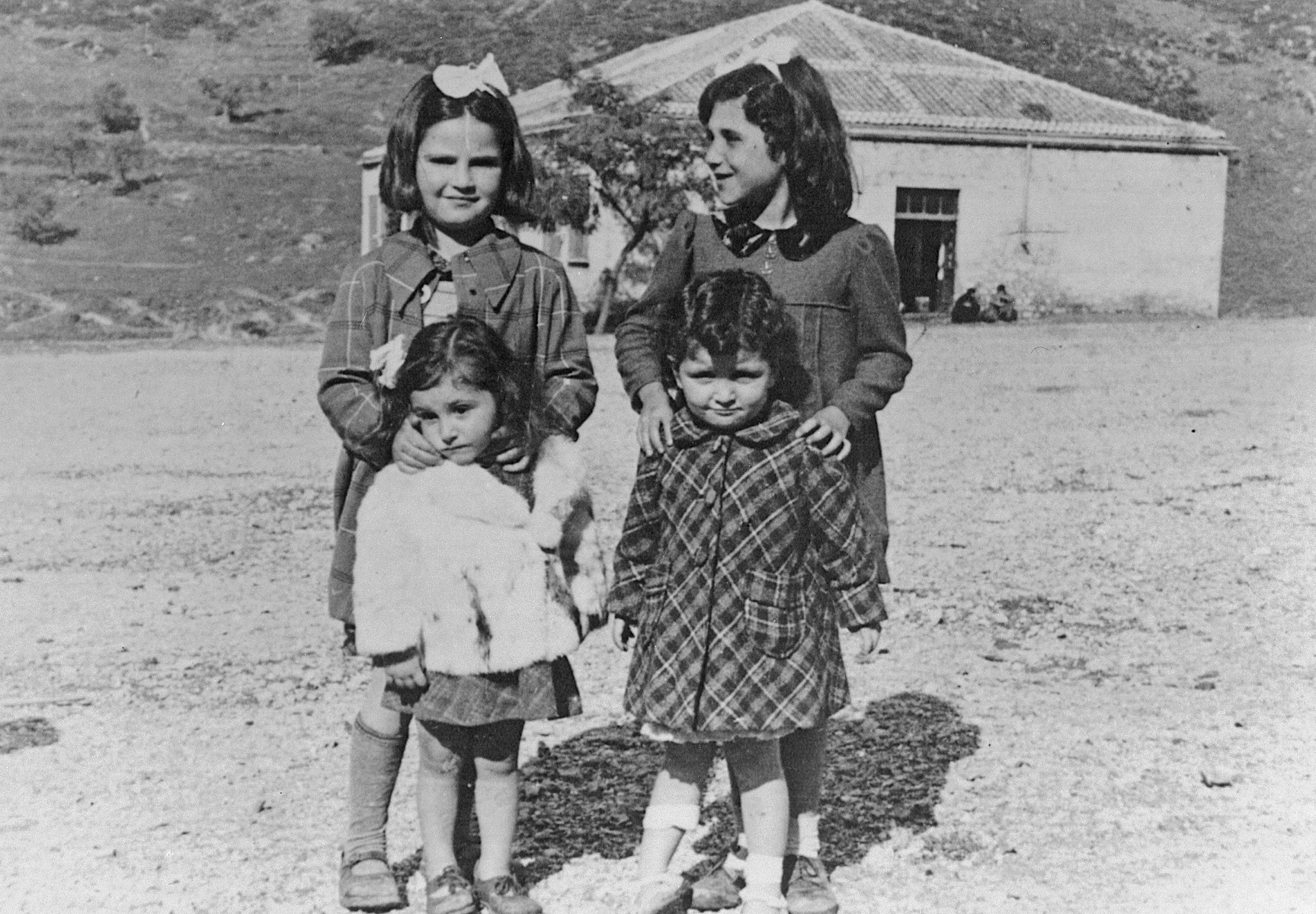 Four young Greek-Jewish cousins visit their grandparents in Delvine, Albania.

Pictured are Gracia Raphael, Graciela Cohen, Eni Cohen, and Ninetta Matsa.

Gracia Raphael was deported from Greece to Auschwitz, where she perished. Graciela and Eni survived in Albania, Ninetta survived in Greece. The Albanian Jewish community was unharmed during the Holocaust.
 
Graciela and Eni immigrated with their families to the United States 1991 after the collapse of Communism in Albania.