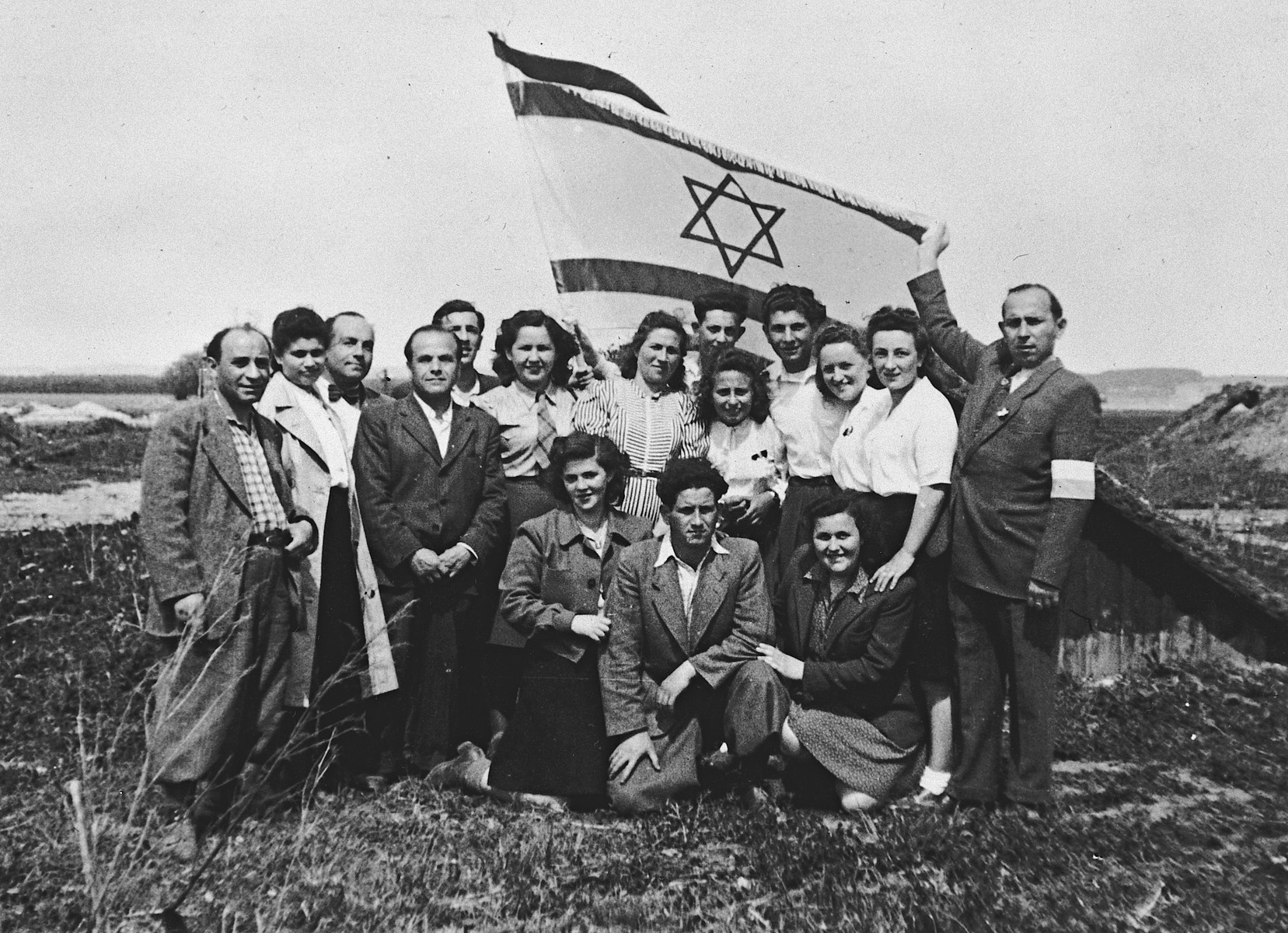 Jewish displaced persons n the Landsberg camp gather for a group portrait underneath a large Israeli flag.

Among those pictured are Max Freidberg (third from left) and Rachel Freidberg (sixth from left in a white blouse and tie).