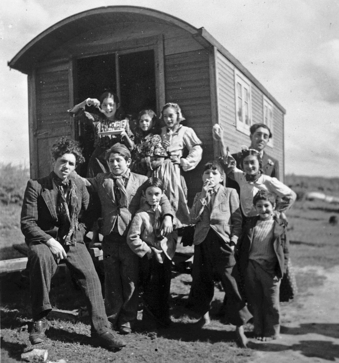 Romani children and youth pose around the entrance to a caravan.

The caption in "The Historic Present" reads, "Europe, 1930s."