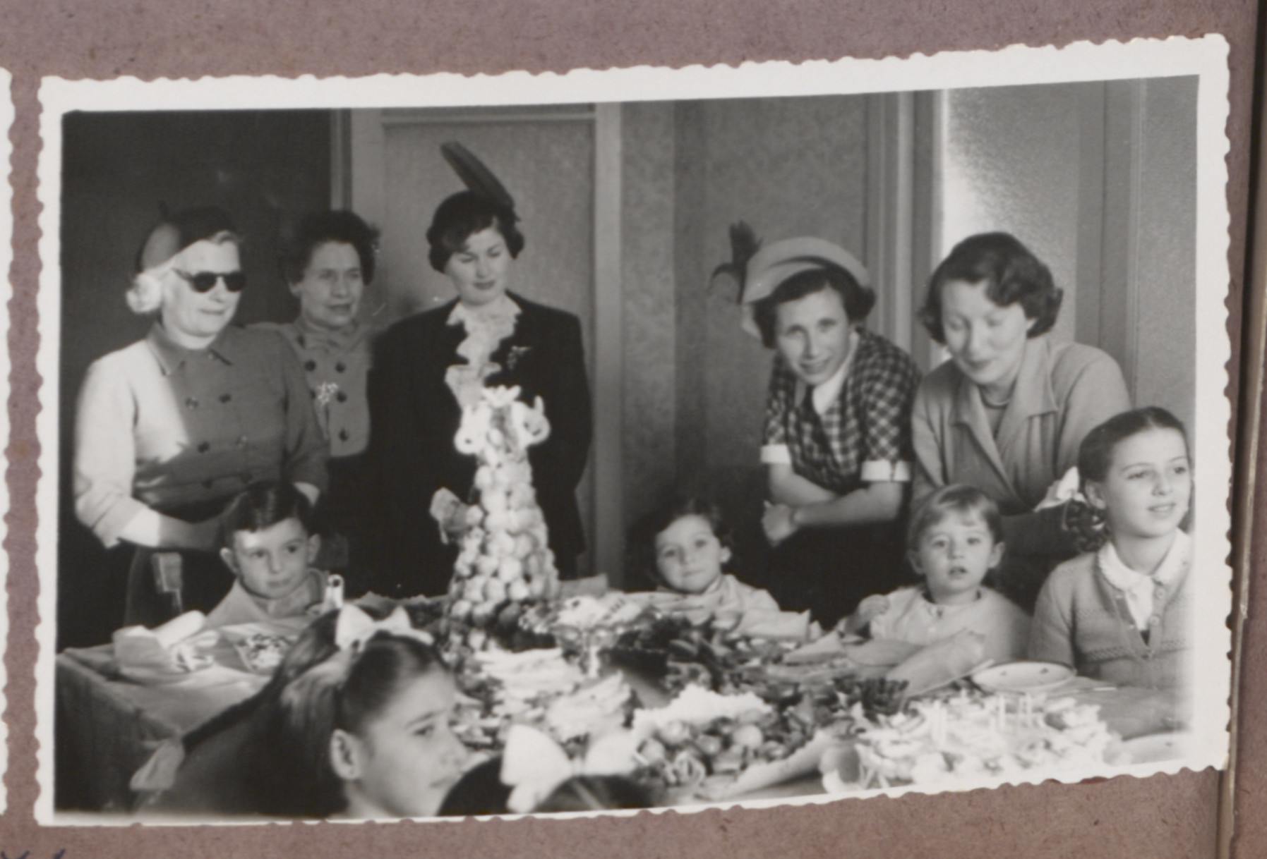 Photo album page showing Daisy Breuer's 7th birthday party with many Hungarian Jewish survivor children in attendance.