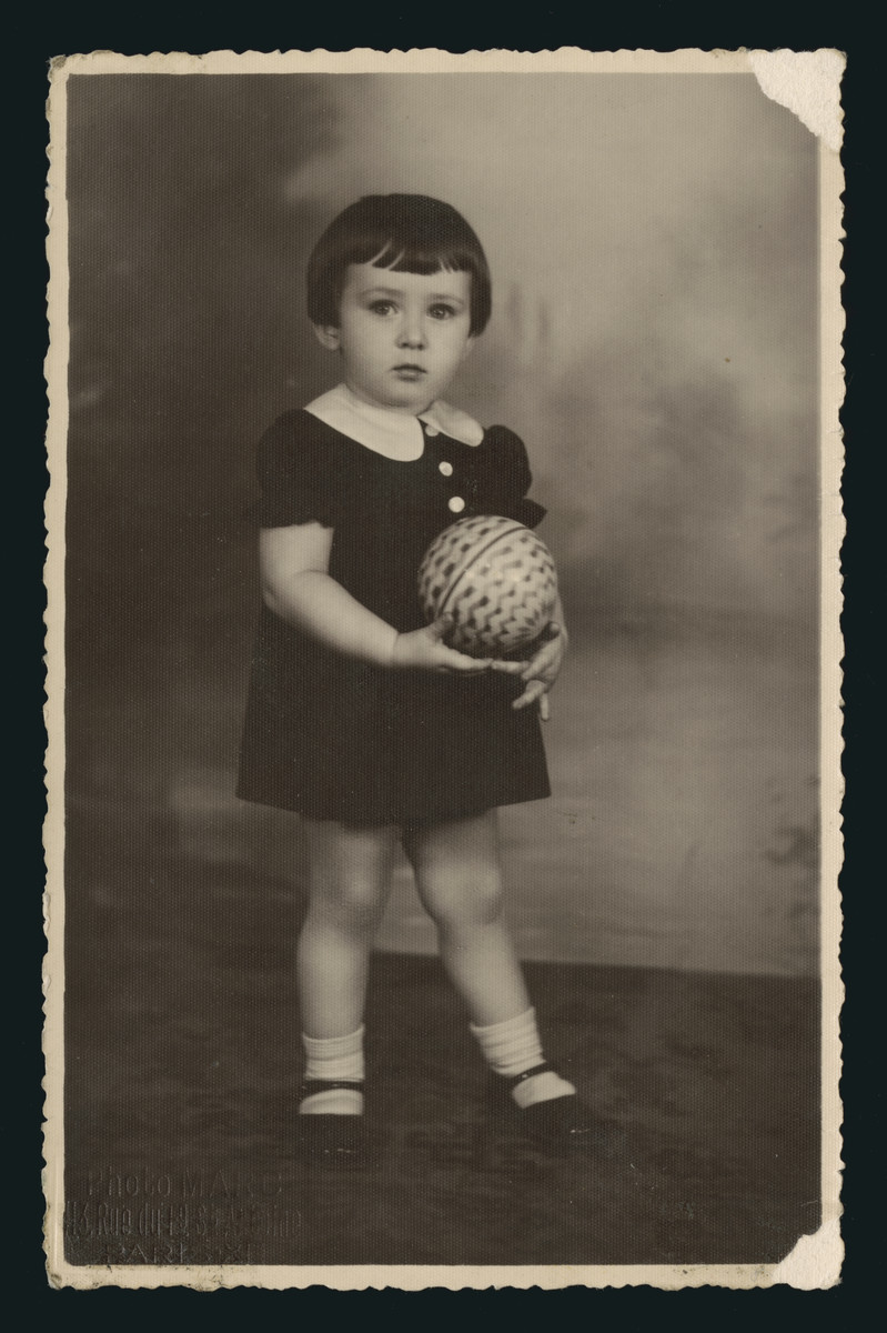 Studio portrait of Denise Rewzin holding a ball.  She is the daughter of a family from Eisiskes.