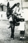 Ora stands next to her rescuer who is riding a donkey.