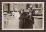 Manya Kirstein supports her baby daughter Sara who is sitting on a ledge [probably in the Weilheim displaced persons camp].