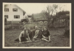 Five friends sit in a field across from an army  truck [probably in the Weilheim displaced persons camp].