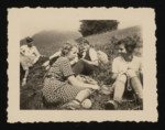 Students from the Goldschmidt School sit outdoors on a grassy hill.