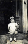 A Bulgarian Jewish child stands in the doorway of a photography studio.