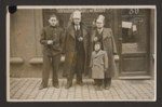 A Jewish father and son stand in front of the family store with two companions.