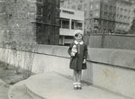 Hana Lustig poses on a sidewalk holding her doll.