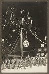 Children's toys, including tin Nazi stormtroopers and a toy ship with a Nazi flag are displayed before a Christmas tree.