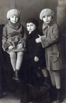 Hana (left) and her sister Irena (right) pose for a studio portrait with an unidentified child wearing coats sewn by a relative.