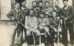 Group portrait of a Soviet soldier and liberated prisoners, some holding weapons, in the Buchenwald concentration camp.