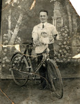 Zvi Hirsch Szklut poses for a studio portrait with his infant daughter Leah and a bicycle.