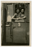 Magda and Gloria Herskovits, and their friend Muschca pose in the window of a train as they leave for America.