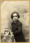 Studio portrait of Paulette Feiler standing next to a table in school, rue Beliard Paris 18, with a book she received as a first prize for the best student of the year 1939.