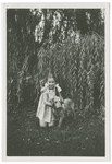 Eight year-old Daisy Goldszpiner (now Daisy Grob), the daughter of Blanche Goldszpiner, poses with a dog in front of a tree in pre-war Warsaw.
