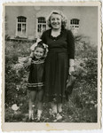 A mother and her young daughter stand in a patch of wild flowers in the Schlachtensee displaced persons' camp.