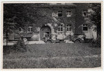 Exterior view of the front of the Landsberg prison with several military vehicles parked outside.