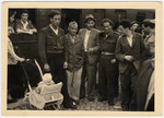 A group of Jewish men and women, one pushing a baby stroller, from the Bergen-Belsen displaced persons camp pose at the train station.