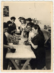 Men and women work at a wooden work table in the ORT dental technicians school in the Bergen-Belsen displaced persons camp.