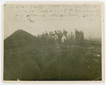 A group of people stand in a field next to a large pit.
