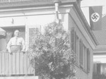 Felix Streim poses on the balcony of his apartment in Germany while a Nazi flag hangs in the background.