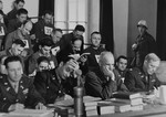 The defendants in the trial of 61 former camp personnel and prisoners from Mauthausen sit behind a group of American military lawyers, who have been assigned to defend them.